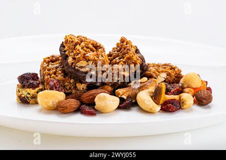 Closeup view of homemade peanuts, almond and chocolate mini protein bars on pile of mixed fruits and nuts on wooden board. Stock Photo