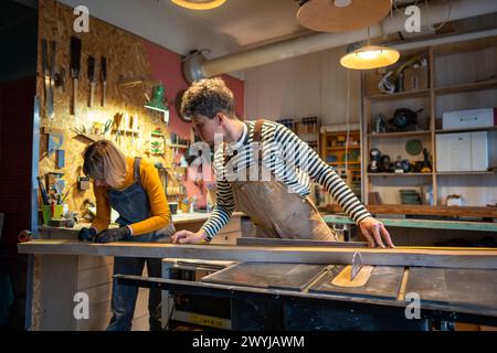 Craftsmen work in carpentry workshop. Professionals working with wood, taking measurements Stock Photo