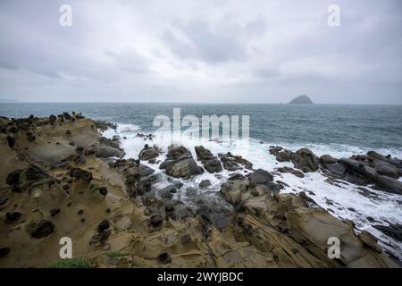 Foreboding skies over a rugged coastline with waves crashing against uniquely eroded rocks Stock Photo