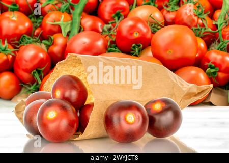 Several ripe black cherry tomatoes with a paper bag, macro, on a background of vegetables. Stock Photo