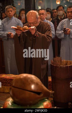 A monk deeply engrossed in prayer using prayer beads during a solemn religious Chinese New Year ceremony Stock Photo