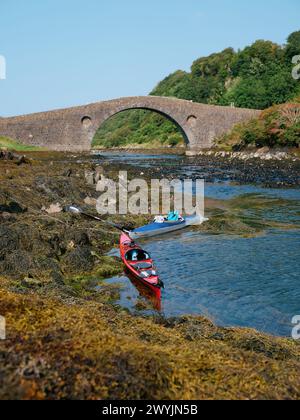 Two touring kayaks at Clachan Bridge a simple, single-arched, hump-backed, masonry bridge spanning the Clachan Sound,Seil, Argyll Scotland UK Stock Photo