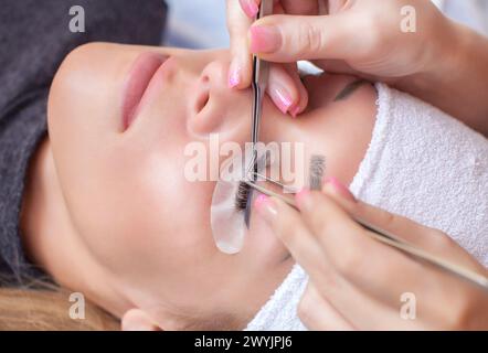 Eyelash extension procedure. Beautiful Woman with long lashes in a beauty salon. Stock Photo