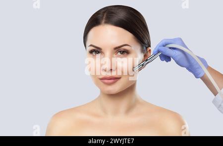 There is a woman, who is making the procedure Microdermabrasion of the facial skin in a beauty salon.Cosmetology and professional skin care. Stock Photo