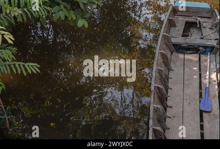 Rowboat moored to along the canal amongst trees and water in rural landscape. Space for text, Selective focus. Stock Photo
