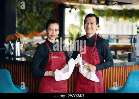 Portrait of smiling cafe waiters cleaning glassware before event Stock Photo