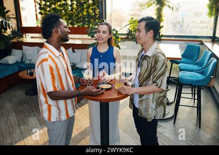 Young people having snacks, drinking and talking at party Stock Photo