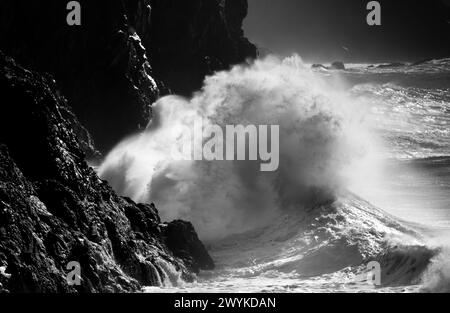 Huge breaker in stormy sea crashing on the cliff at Kynance Cove on the Lizard Peninsula, Cornwall.  Monochrome image. Stock Photo