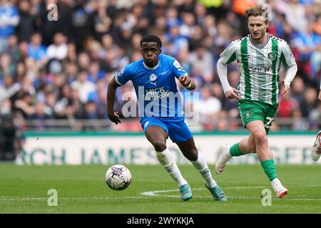 Peterborough United's Kwame Poku in action against Wycombe Wanderers's Kieran Sadlier (right) during the Bristol Street Motors Trophy final at Wembley Stadium, London. Picture date: Sunday April 7, 2024. Stock Photo