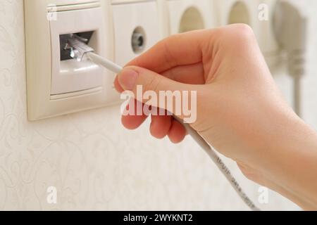 A woman's hand connects the Internet cable to a socket, rj-45 Stock Photo