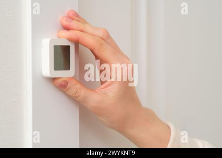 A woman's hand sets a thermometer on the wall, close-up Stock Photo