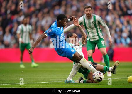 Peterborough United's Kwame Poku attempt on goal despite a tackle from Wycombe Wanderers's Nigel Lonwijk during the Bristol Street Motors Trophy final at Wembley Stadium, London. Picture date: Sunday April 7, 2024. Stock Photo