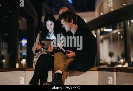 Entrepreneurs in informal outdoor meeting at night discussing over digital tablet Stock Photo