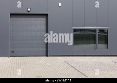 Gray industrial wall with roller shutter door and window. Modern Industrial Building Facade Stock Photo