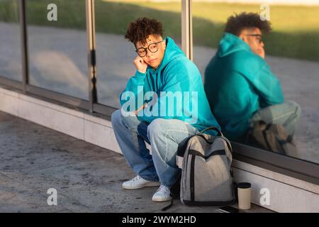 Young guy student sitting outside with reflection Stock Photo