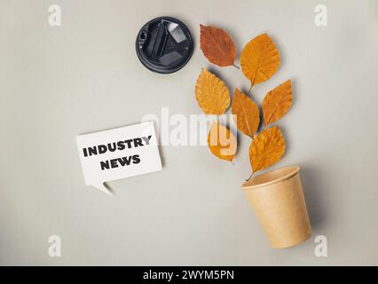 A sign that says Industry News is on a grey background. There is a potted plant with leaves on it Stock Photo