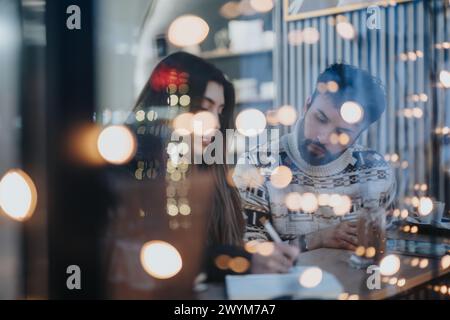 Two young professionals collaborating late at night in a cozy workspace. Stock Photo