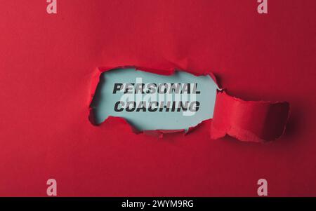 A red piece of paper with the word personal coaching written in black. The paper is torn open, revealing the word "personal" in white Stock Photo