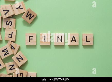 A pile of wooden blocks with the word final written on them. The blocks are scattered around the word, creating a sense of disarray and chaos. The ima Stock Photo
