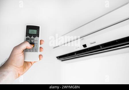 Hand holding remote control in front of the air conditioner. Stock Photo