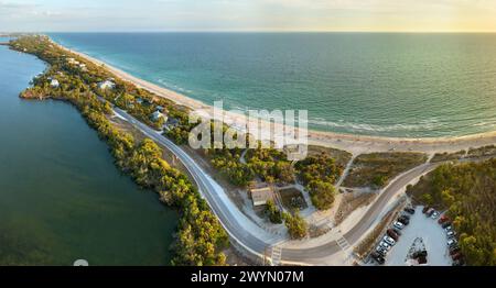 Parking lot for tourists cars in front of ocean beach with soft white sand in Florida. Popular vacation spot at sunset Stock Photo