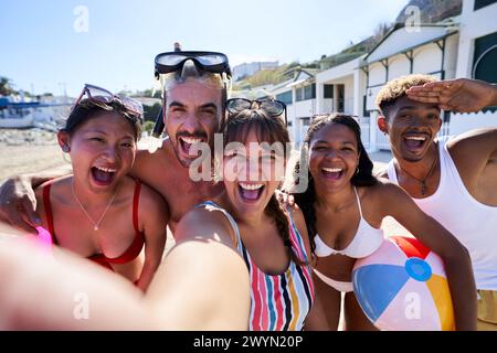 Cheerful Selfie of multiracial group of friends on the beach having fun outdoors looking at camera. Stock Photo