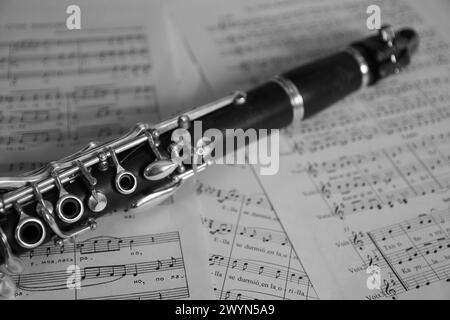 Close-up of a clarinet, a typical wind instrument used in bands, on some music sheets. Black and white image Stock Photo