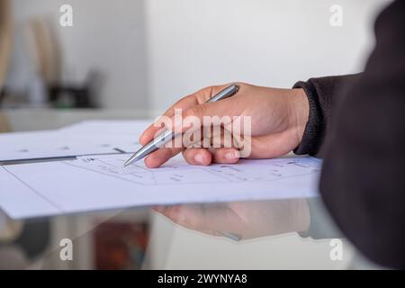 male holding pen while checking projects papers on glass table with reflections Stock Photo