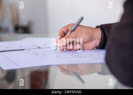 male holding pen while checking projects papers on glass table with reflections Stock Photo