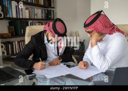 Senior arabic male check his junior work and make sure he can fix it Stock Photo
