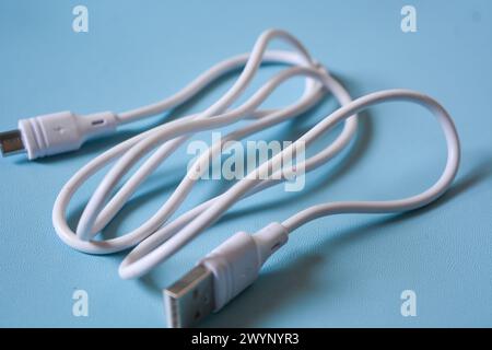 White folded usb and micro usb cable on blue background. Stock Photo