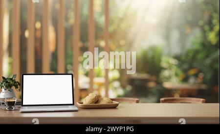 A laptop computer with a white screen mockup on a rustic wooden table in a beautiful green restaurant or cafe garden on a sunny day, illuminated by fa Stock Photo