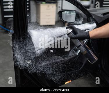 A man sprays cleaning foam on the interior of a car. Stock Photo