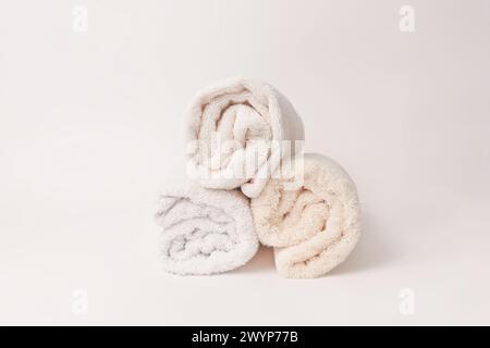 Clean rolled beige soft bath towels stack on a white background Stock Photo