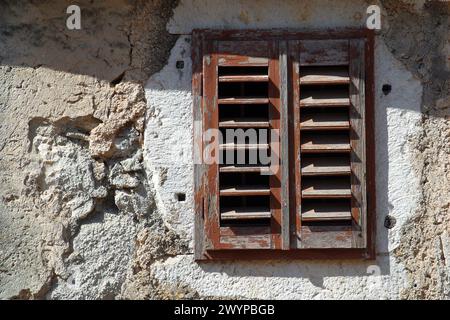 Window with closed wooden shutters on an old abandoned traditional house in Lun, island of Pag, Croatia Stock Photo