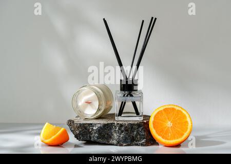 Elegant Aroma Diffuser With Black Reeds on a Slate Base Next to a Fresh Orange Slice Stock Photo