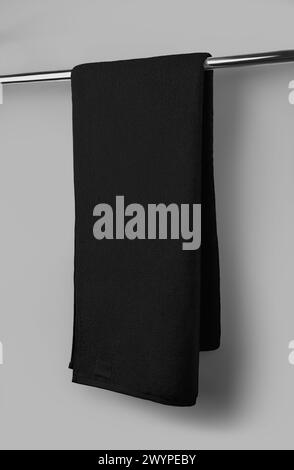 Mockup of black terry towel with label, folded, hanging on a tube, isolated on background. Fluffy towelling template for wiping, for design, branding. Stock Photo