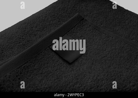 Mockup of a black terry towel with a label, folded in half, for design, branding. Template of fluffy towelette for wiping the body, isolated on backgr Stock Photo