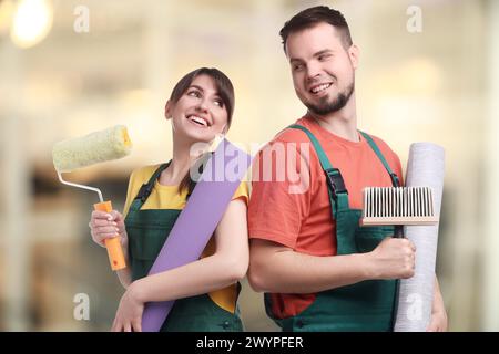 Workers with wallpaper rolls and tools indoors Stock Photo