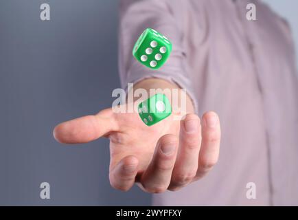 Man throwing green dice on grey background, closeup Stock Photo