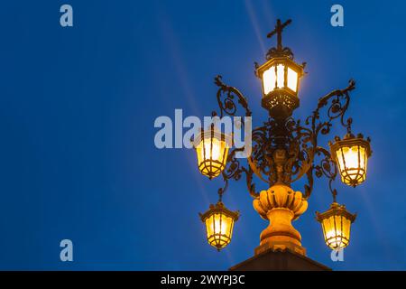 Ornate lamp post of Fuente de la Farola fountain illuminated at night, isolated against evening sky in Seville, Andalusia, Spain. Stock Photo