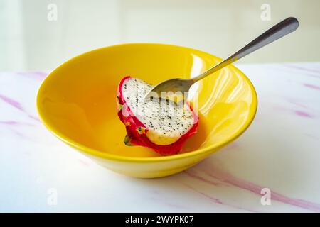 Dragon fruit in a yellow bowl with spoon. Delicious cut and whole dragon fruit pitahaya. Stock Photo