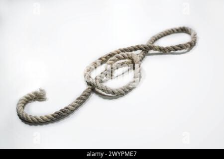 Old rough rope laying in the shape of a treble clef or violin key on a light gray background, musical symbol, copy space, selected focus, narrow depth Stock Photo