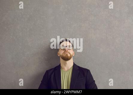 Serious caucasian man with a pensive and dubious expression looks up over his head. Stock Photo
