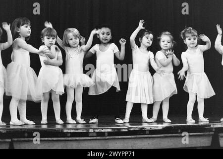 A line of girl infants perform a song with actions for parents at a dance class show in south London, on 18th December 1998, in London, England. Stock Photo