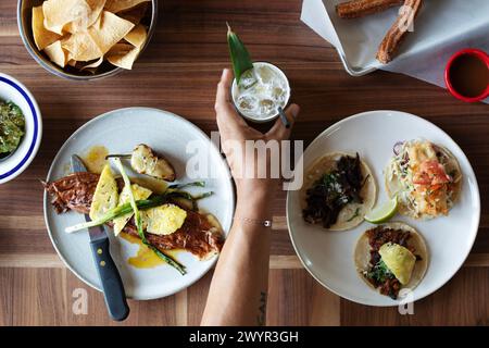 Hand setting drink on table full of food dishes Stock Photo