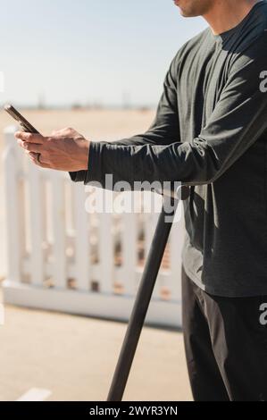 Man using smartphone while on an electric scooter at the beach Stock Photo