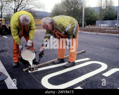 Painting road markings on road surface in car park Stock Photo