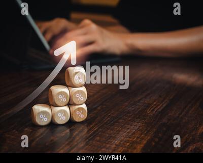 Rise up arrow on wooden cube blocks as a business growth graph steps with percentage icon while businessman using laptop computer with copy space. Inv Stock Photo