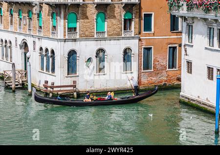 Classic view from the Rialto Bridge of the Grand Canal with tourists enjoying a traditional  boat trip in a gondola ride in Venice, Italy Stock Photo